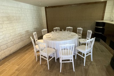 Entrée d'un bâtiment beige avec une toiture rouge, entourée de palissades en bois et d'une pelouse artificielle.