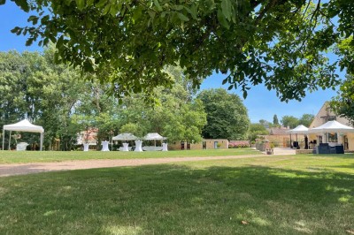 Miniature Location salle Le Bernard (Vendée) - La Grange du Prieuré #16 Centre de table avec des fleurs roses et blanches dans un vase doré, entouré de bougies et de verres sur une nappe blanche.