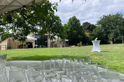 Miniature Location salle Le Bernard (Vendée) - La Grange du Prieuré #17 Centre de table avec des fleurs roses et blanches dans un vase doré, entouré de bougies et de verres sur une nappe blanche.