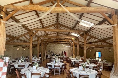 Miniature Location salle Le Bernard (Vendée) - La Grange du Prieuré #8 Centre de table avec des fleurs roses et blanches dans un vase doré, entouré de bougies et de verres sur une nappe blanche.