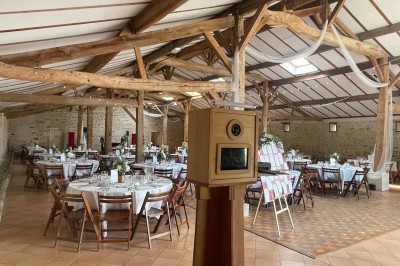 Miniature Location salle Le Bernard (Vendée) - La Grange du Prieuré #9 Centre de table avec des fleurs roses et blanches dans un vase doré, entouré de bougies et de verres sur une nappe blanche.