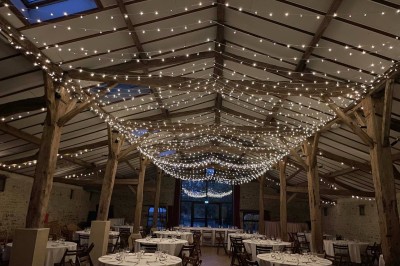 Miniature Location salle Le Bernard (Vendée) - La Grange du Prieuré #4 Centre de table avec des fleurs roses et blanches dans un vase doré, entouré de bougies et de verres sur une nappe blanche.