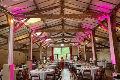 Miniature Location salle Le Bernard (Vendée) - La Grange du Prieuré #5 Centre de table avec des fleurs roses et blanches dans un vase doré, entouré de bougies et de verres sur une nappe blanche.