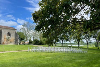 Miniature Location salle Le Bernard (Vendée) - La Grange du Prieuré #22 Centre de table avec des fleurs roses et blanches dans un vase doré, entouré de bougies et de verres sur une nappe blanche.