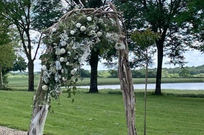Miniature Location salle Le Bernard (Vendée) - La Grange du Prieuré #24 Centre de table avec des fleurs roses et blanches dans un vase doré, entouré de bougies et de verres sur une nappe blanche.