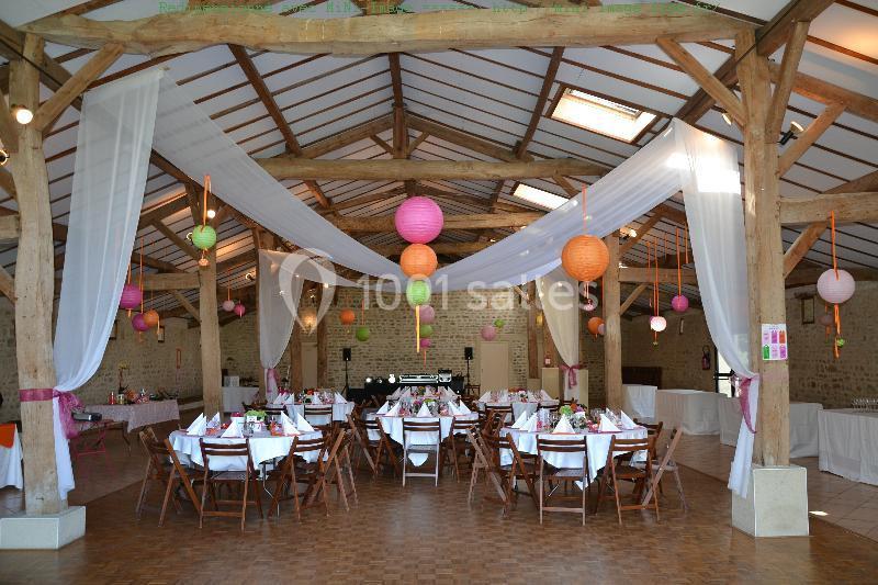Salle de réception décorée avec des guirlandes et lanternes colorées, tables dressées pour un événement festif.