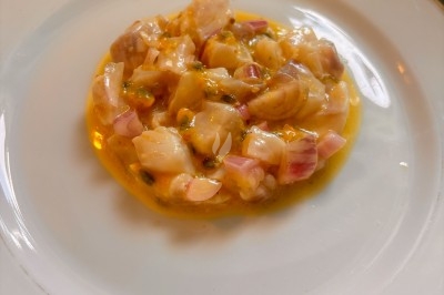 Miniature Traiteur Rennes (Ille-et-Vilaine) - Boeuf Carottes #5 Carpaccio de poisson blanc nappé d'une sauce citronnée, garni de fines herbes et d'épices, servi dans une assiette blanche.