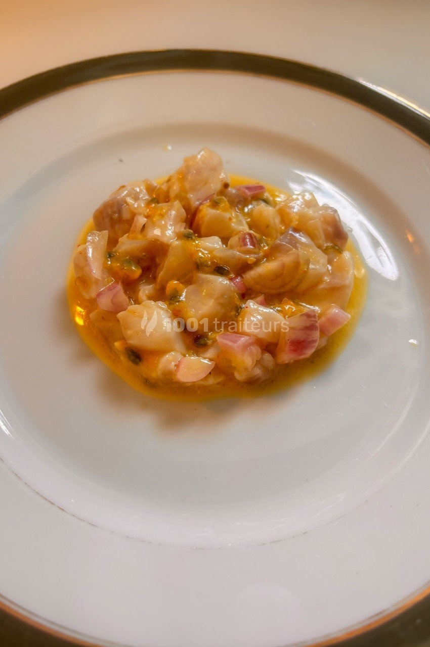 Assiette de tartare de poisson cru, coupé en morceaux, servi avec une sauce légèrement orangée.