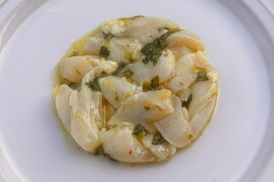 Miniature Traiteur Rennes (Ille-et-Vilaine) - Boeuf Carottes #9 Carpaccio de poisson blanc nappé d'une sauce citronnée, garni de fines herbes et d'épices, servi dans une assiette blanche.