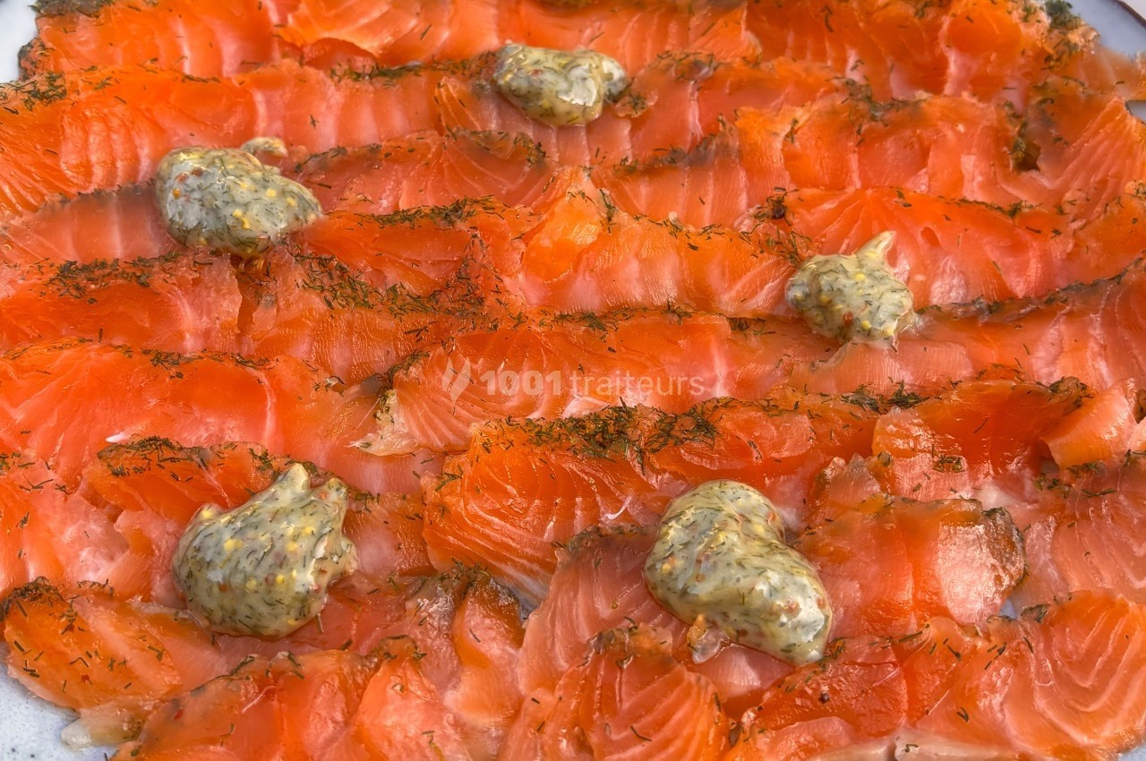 Tranches de saumon gravlax garnies de petites touches de moutarde à l'aneth sur une assiette.