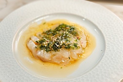 Miniature Traiteur Rennes (Ille-et-Vilaine) - Boeuf Carottes #14 Carpaccio de poisson blanc nappé d'une sauce citronnée, garni de fines herbes et d'épices, servi dans une assiette blanche.