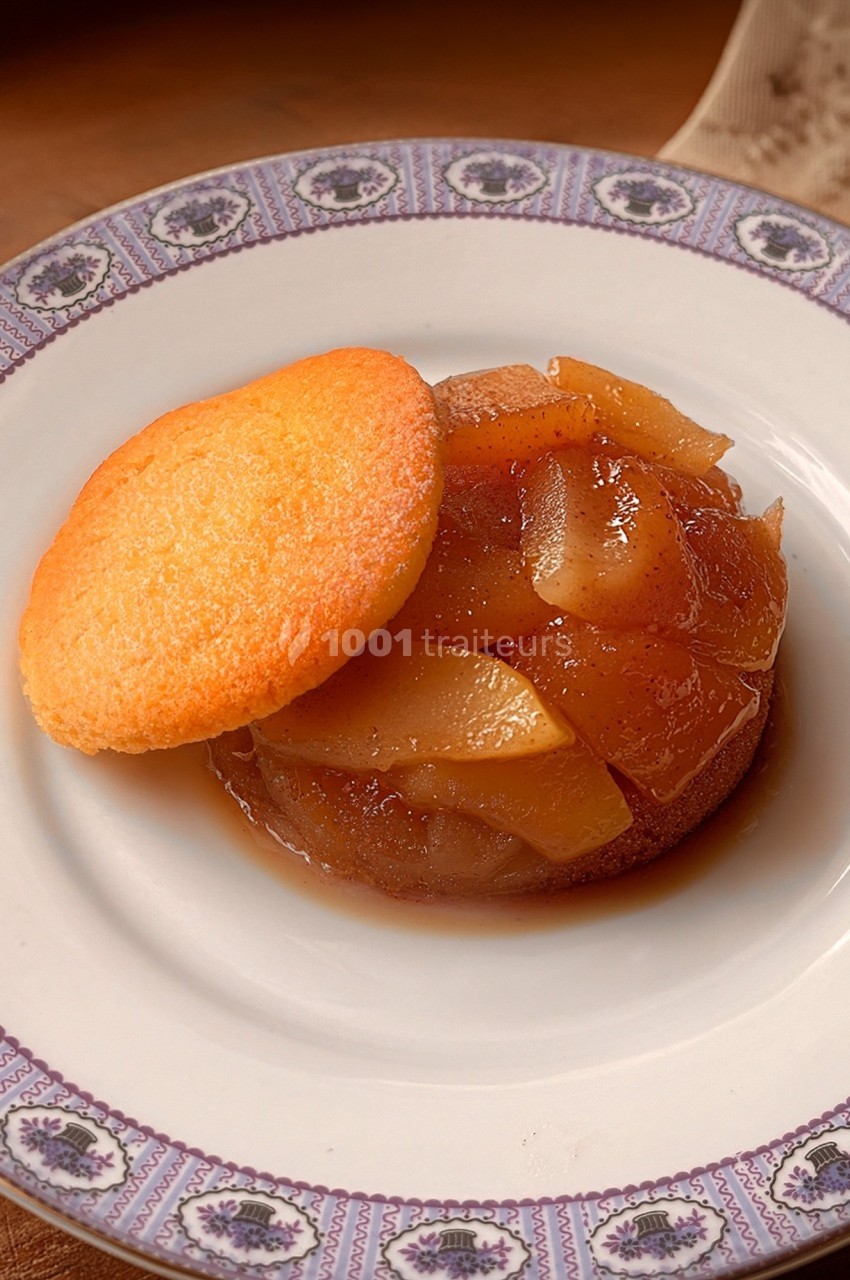 Tartelette tatin aux pommes caramélisées, servie avec un biscuit doré sur une assiette décorative.