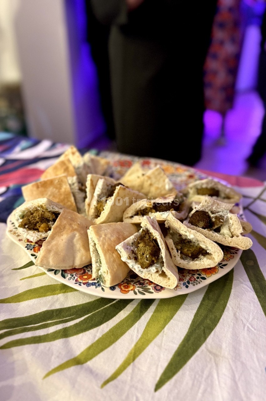 Assiette de pita garnie de falafels et de sauce, posée sur une nappe colorée dans un cadre intérieur.
