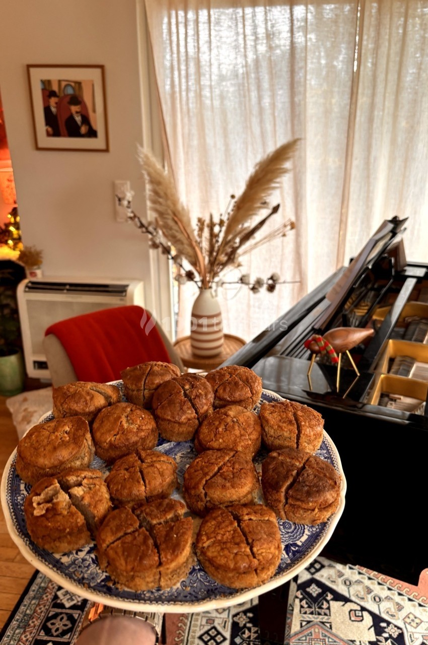 Assiette de petits pains dorés présentée dans un salon chaleureux avec un piano et une décoration cosy en arrière-plan.