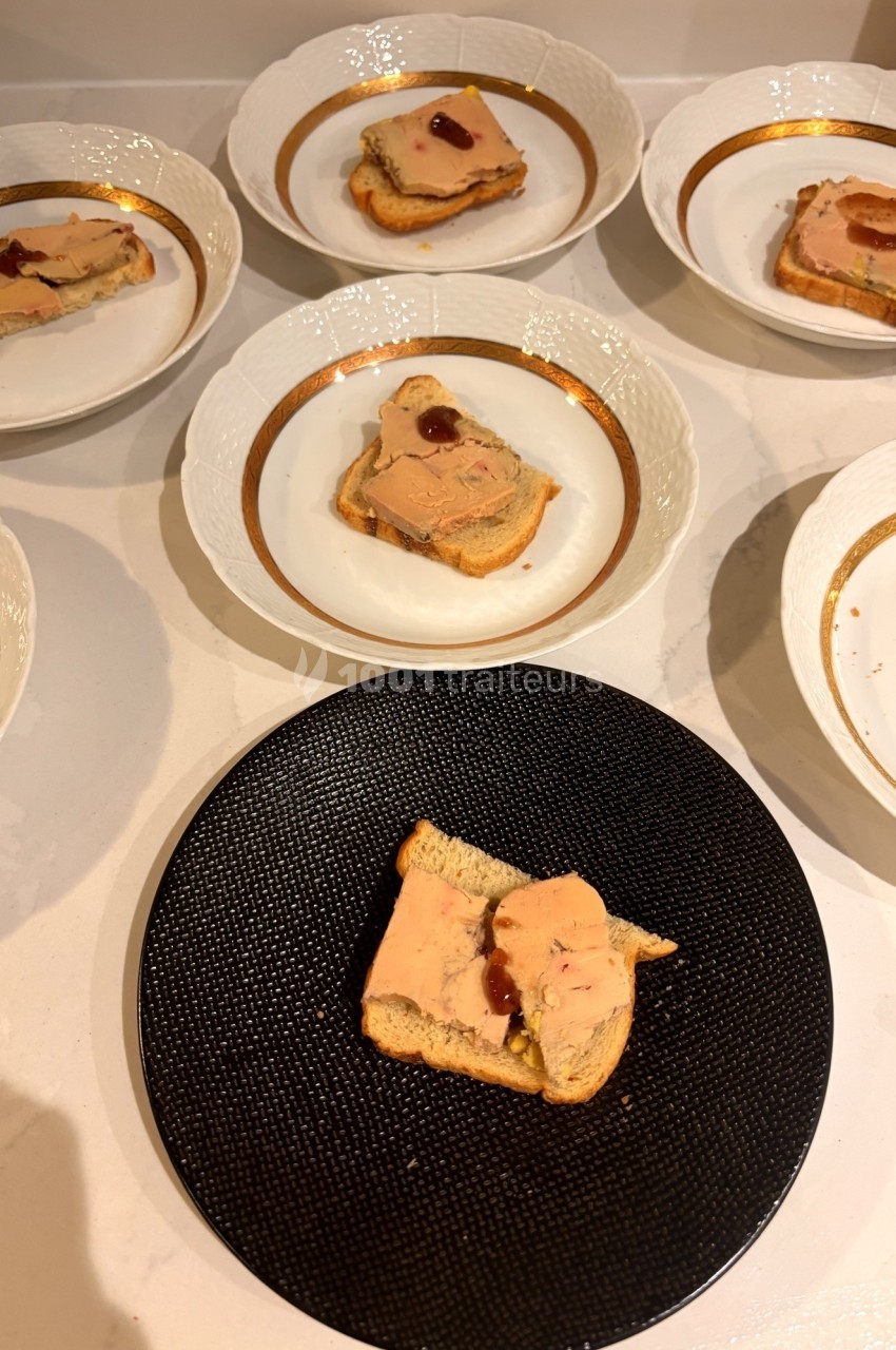 Tranches de foie gras sur des toasts, présentées dans des assiettes blanches et une assiette noire.