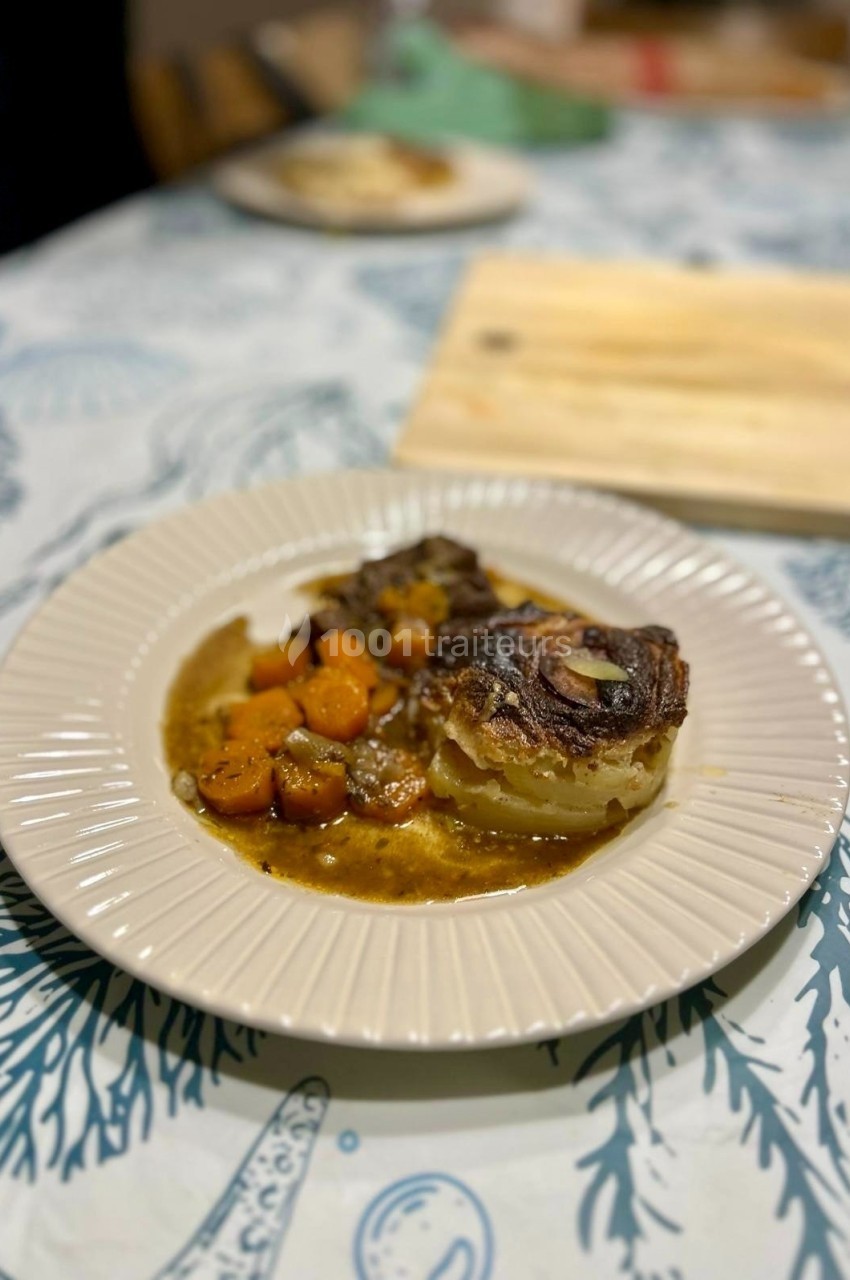 Assiette contenant un gratin de pommes de terre et des légumes racines cuits dans une sauce brune.