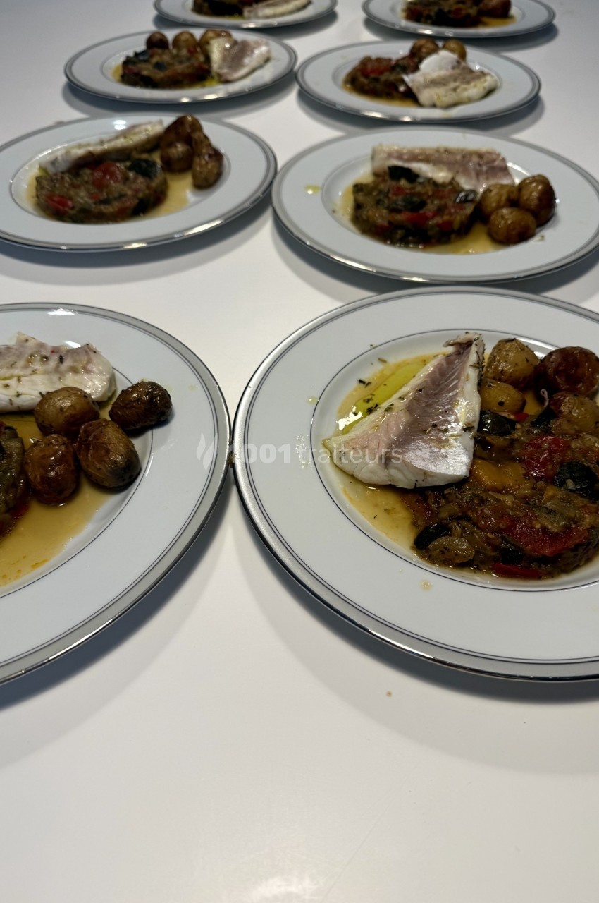 Assiettes dressées avec filet de poisson, légumes grillés et pommes de terre rôties sur une table blanche.