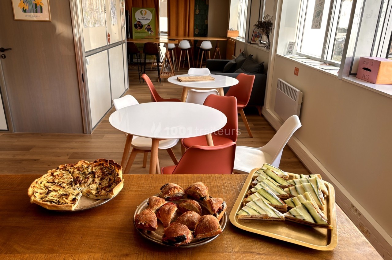 Plats de viennoiseries, tartes et toasts disposés sur une table en bois dans un espace de restauration lumineux.