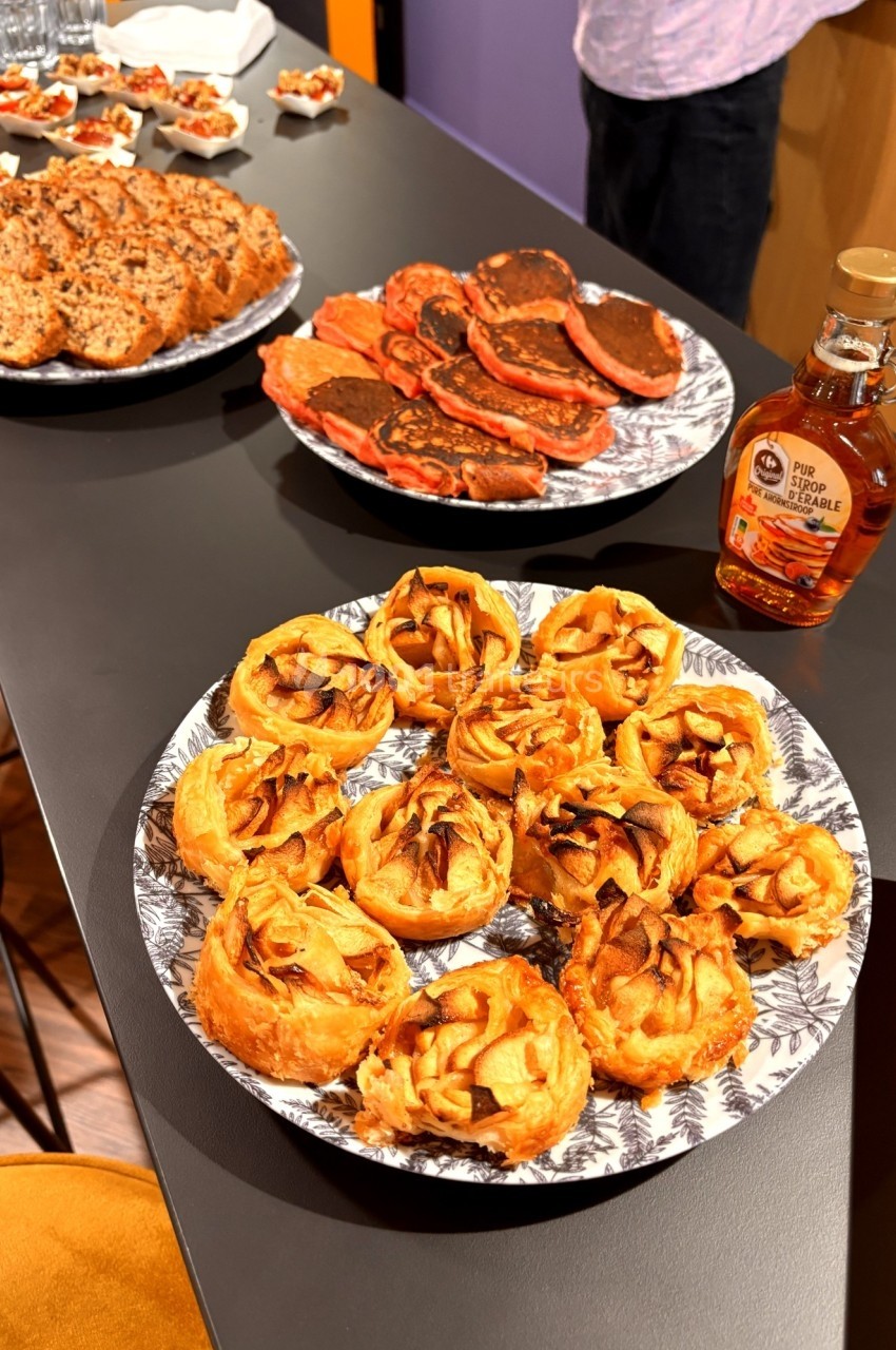 Assortiment de pâtisseries et crêpes sur une table, accompagné d'une bouteille de sirop d'érable.