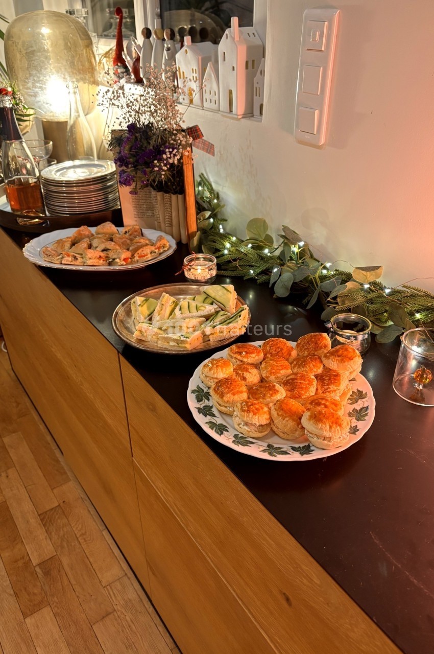 Plateau de petits fours salés et amuse-bouches disposés sur un buffet décoré de guirlandes lumineuses.