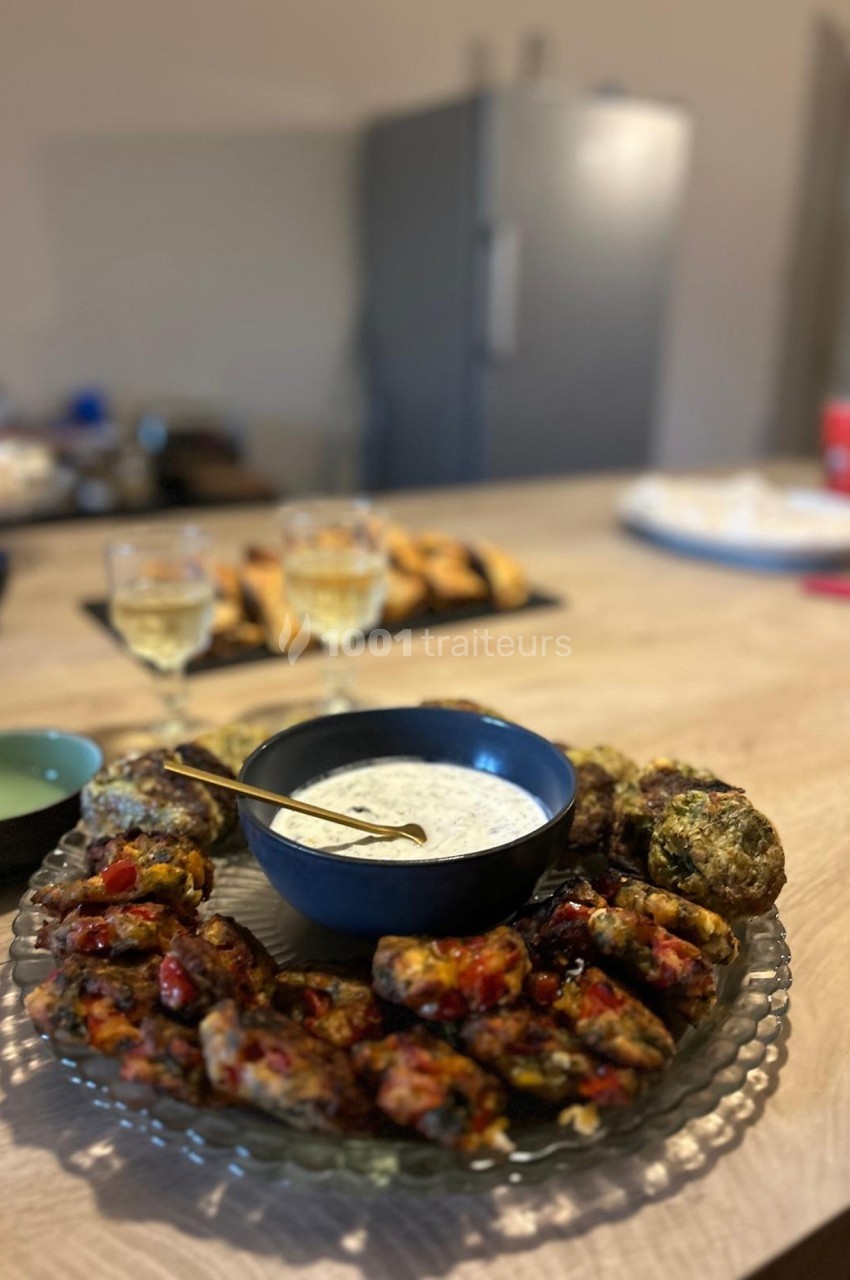 Assiette de boulettes de légumes servie avec une sauce blanche, posée sur une table en bois dans une cuisine.