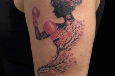 Tatouage floral noir et gris sur une cuisse, représentant des fleurs et des feuilles avec des détails délicats.