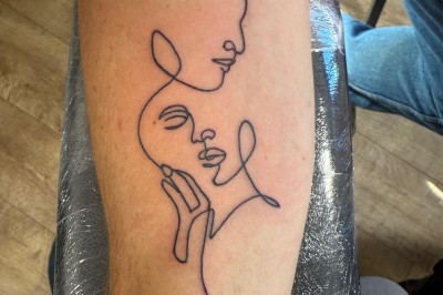 Tatouage floral noir et gris sur une cuisse, représentant des fleurs et des feuilles avec des détails délicats.