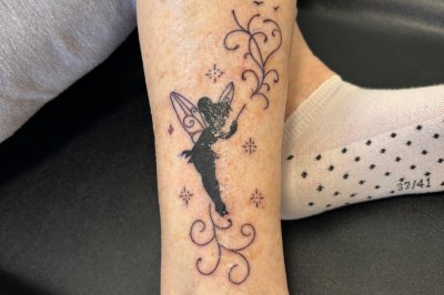 Tatouage floral noir et gris sur une cuisse, représentant des fleurs et des feuilles avec des détails délicats.