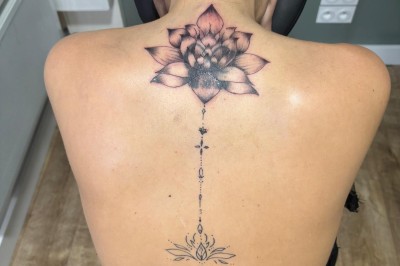 Tatouage floral noir et gris sur une cuisse, représentant des fleurs et des feuilles avec des détails délicats.