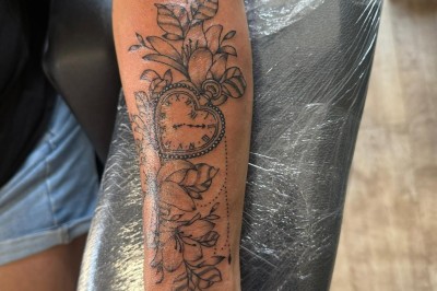Tatouage sur une jambe représentant un papillon dont une aile se transforme en un bouquet de fleurs détaillées.