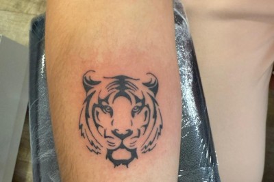 Tatouage sur une jambe représentant un papillon dont une aile se transforme en un bouquet de fleurs détaillées.