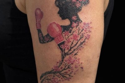 Tatouage sur une jambe représentant un papillon dont une aile se transforme en un bouquet de fleurs détaillées.