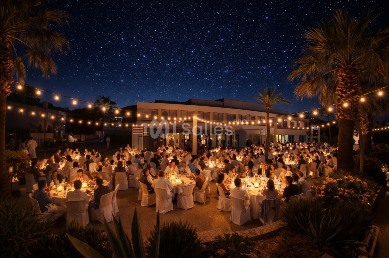 Dîner en plein air sous un ciel étoilé, avec des invités assis à des tables illuminées par des guirlandes lumineuses.