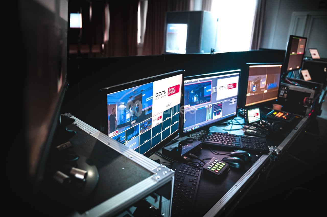Poste de contrôle audiovisuel avec plusieurs écrans affichant des interfaces de production et des équipements techniques.