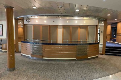 Salle de conférence vide avec rangées de sièges bleus et une estrade équipée de micros en arrière-plan.