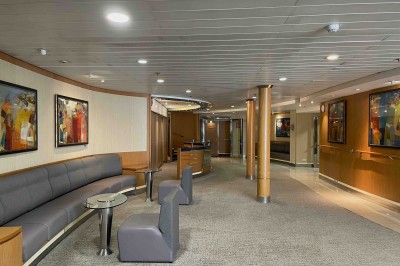 Salle de conférence vide avec rangées de sièges bleus et une estrade équipée de micros en arrière-plan.