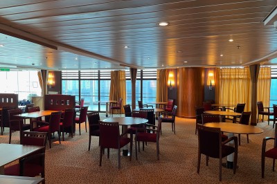 Salle de conférence vide avec rangées de sièges bleus et une estrade équipée de micros en arrière-plan.