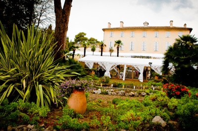 Miniature Location salle La Cadière-d'Azur (Var) - Château de Rochebelle - Var #2 Jardin verdoyant avec des pots en terre cuite et une tente blanche entourée d'arbres et de végétation.