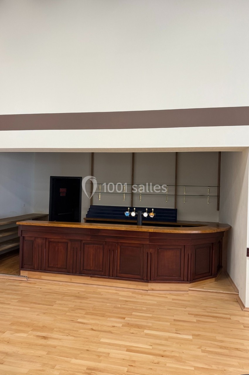 Comptoir en bois sombre dans un espace vide avec étagères murales et sol en parquet clair.