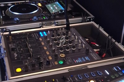 Table de mixage et platines DJ professionnelles avec câblage et éclairages en fonctionnement.