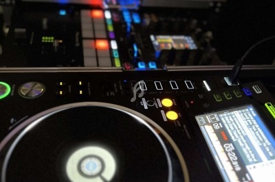 Table de mixage DJ avec platines et contrôles lumineux dans un environnement sombre.