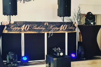 Installation de matériel de sonorisation et éclairage pour une fête d'anniversaire avec une bannière ’Happy 40 Birthday’.