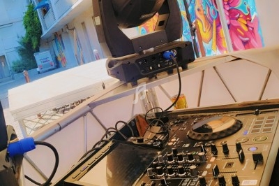 Table de mixage sous un chapiteau, avec des fresques colorées en arrière-plan dans un espace urbain.