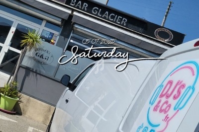 Devanture d'un bar glacier avec une camionnette blanche stationnée au premier plan.
