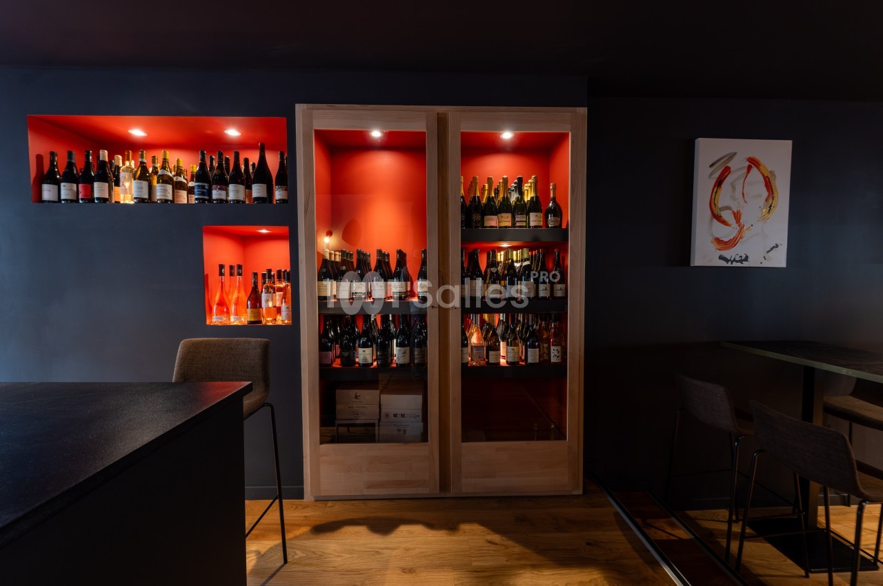 Cave à vin moderne avec étagères éclairées contenant des bouteilles, dans un espace intérieur sombre et élégant.