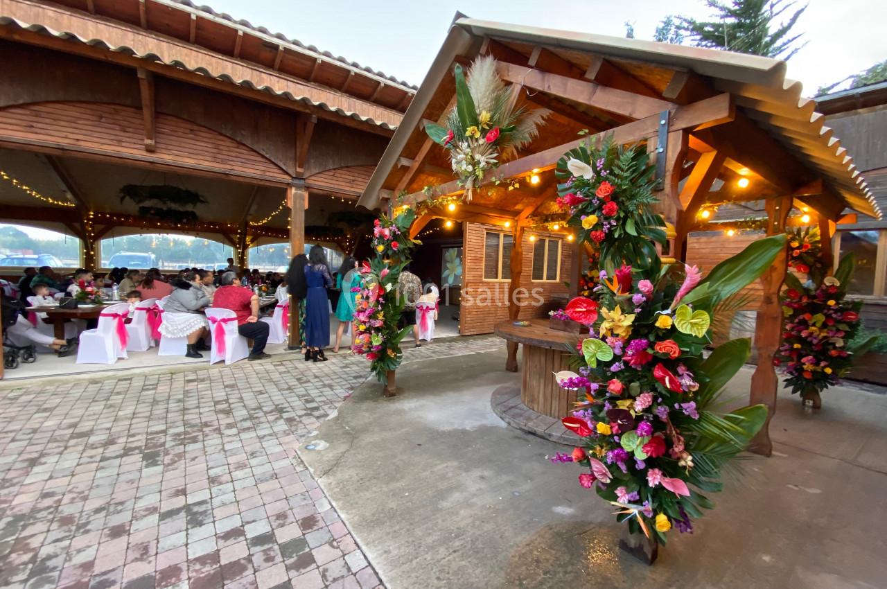 Décoration florale colorée autour d'une petite structure en bois lors d'un événement en plein air sous des pavillons…