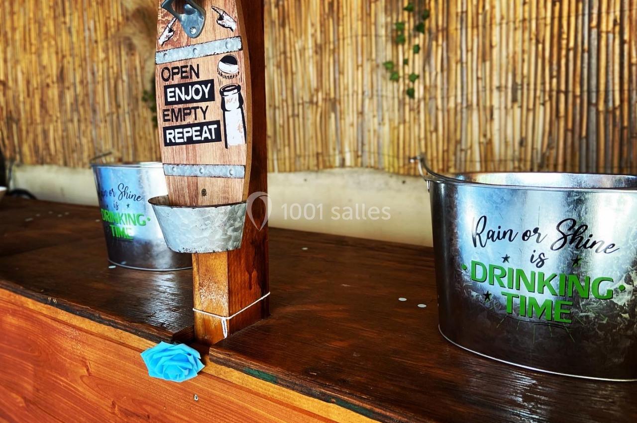 Deux seaux métalliques sur un comptoir en bois, avec un robinet décoratif et un fond en bambou.