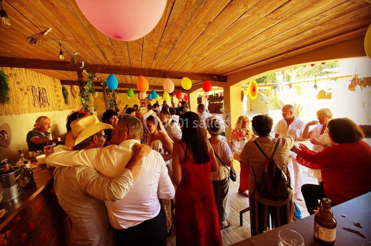 Groupe de personnes rassemblées dans un espace couvert décoré de ballons colorés, lors d'une fête conviviale.