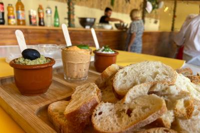 Table en bois garnie de divers plats, pains, charcuteries et amuse-bouches, présentés pour un buffet en extérieur.