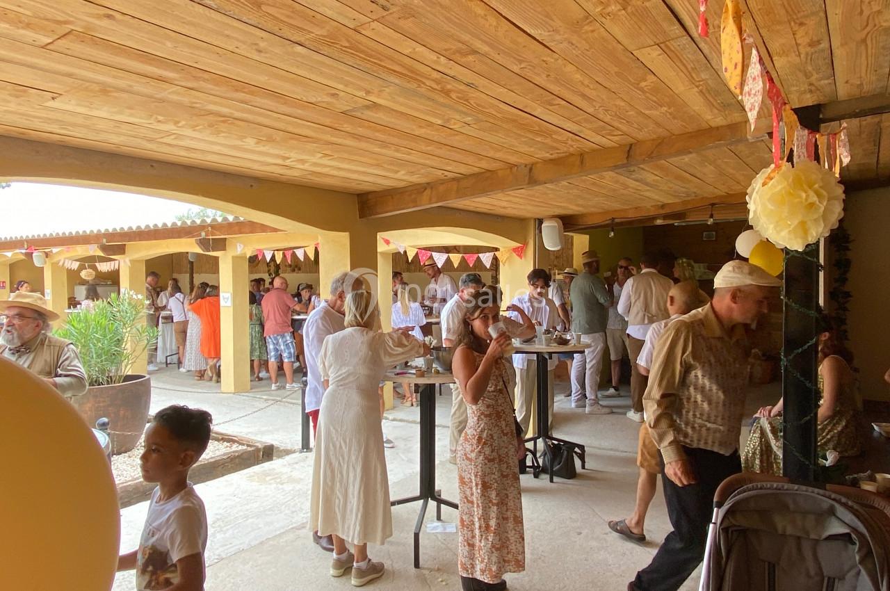Groupe de personnes discutant et partageant un moment convivial dans une cour couverte décorée de guirlandes colorées.